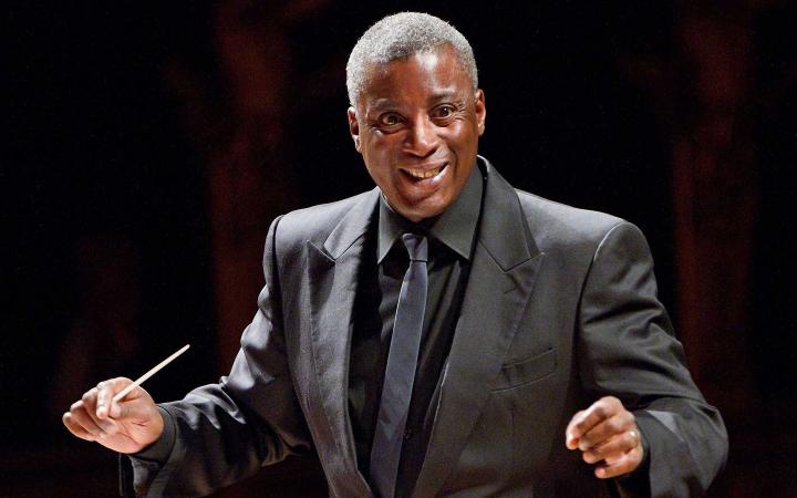 Wayne Marshall mentre dirige, con abito scuro su fondo nero