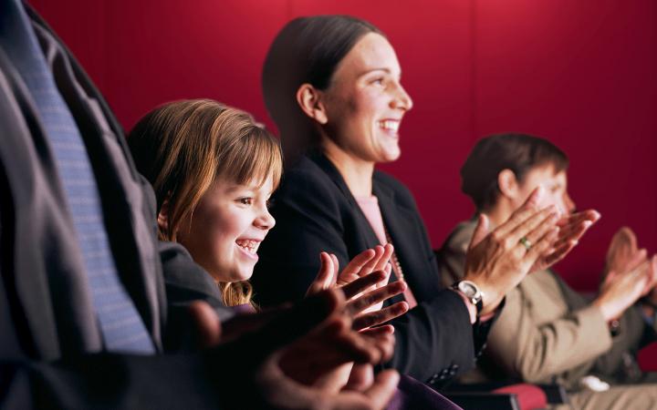 Young girl smiling and clapping together with her mum